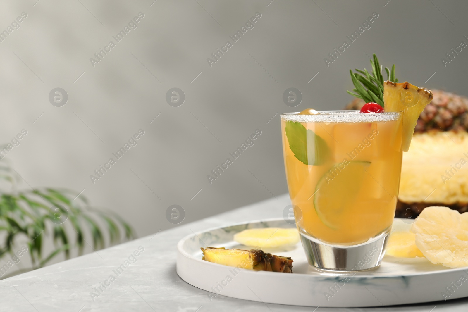 Photo of Glass of tasty pineapple cocktail and fresh fruit on light gray table, space for text