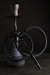 Photo of Modern hookah on black table against dark background