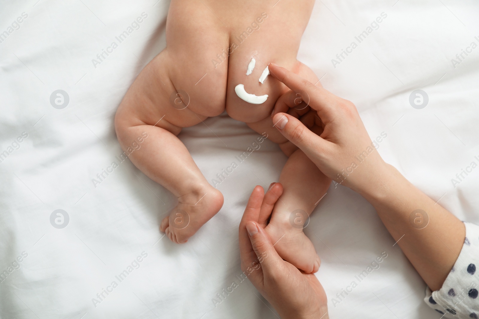 Photo of Mother applying body cream on her little baby, top view