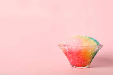 Rainbow shaving ice in glass dessert bowl on pink background, space for text