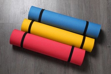 Photo of Bright rolled camping mats on grey wooden background, flat lay