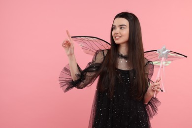 Photo of Beautiful girl in fairy costume with wings and magic wand on pink background. Space for text