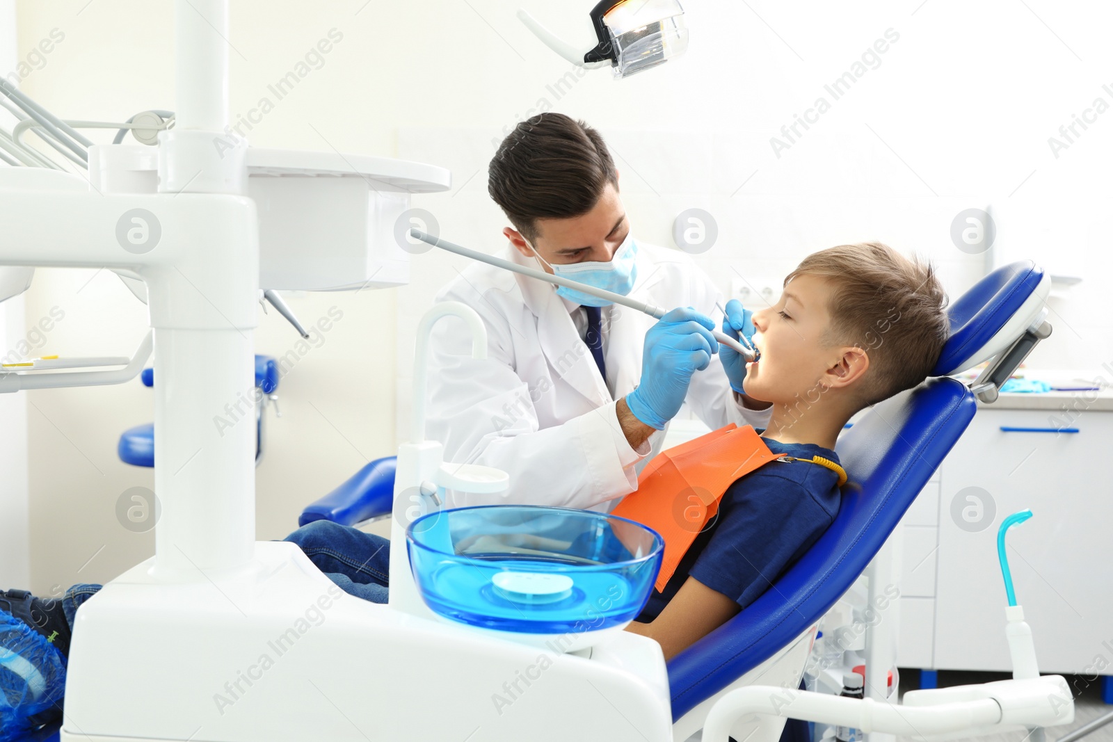 Photo of Professional dentist working with little boy in clinic