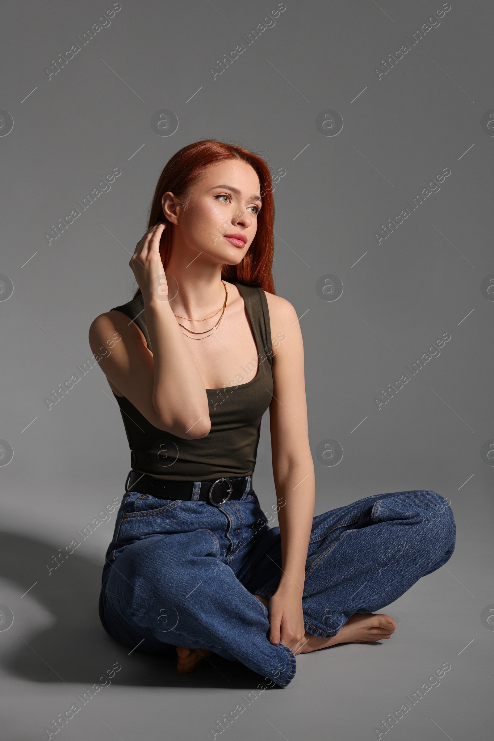 Photo of Beautiful young woman sitting on gray background