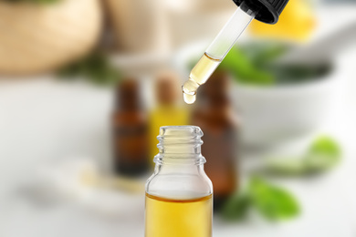 Little bottle with essential oil and dropper against blurred background 