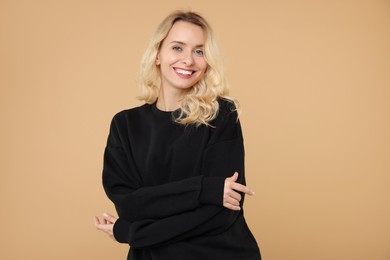 Happy woman in stylish warm sweater on beige background