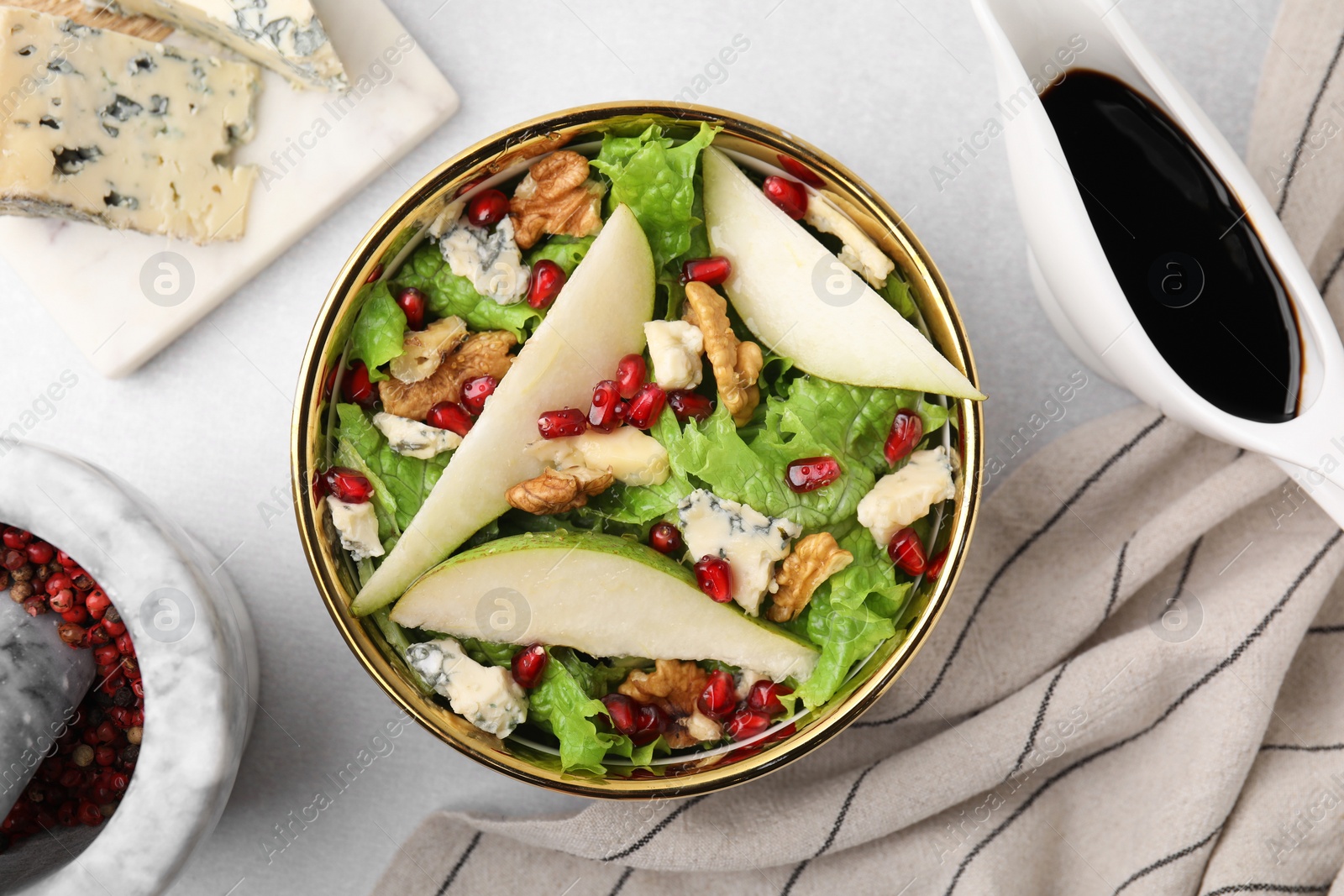 Photo of Delicious pear salad in bowl and sauce on light table, flat lay