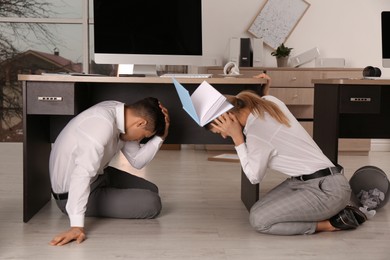 Photo of Scared employees on floor in office during earthquake