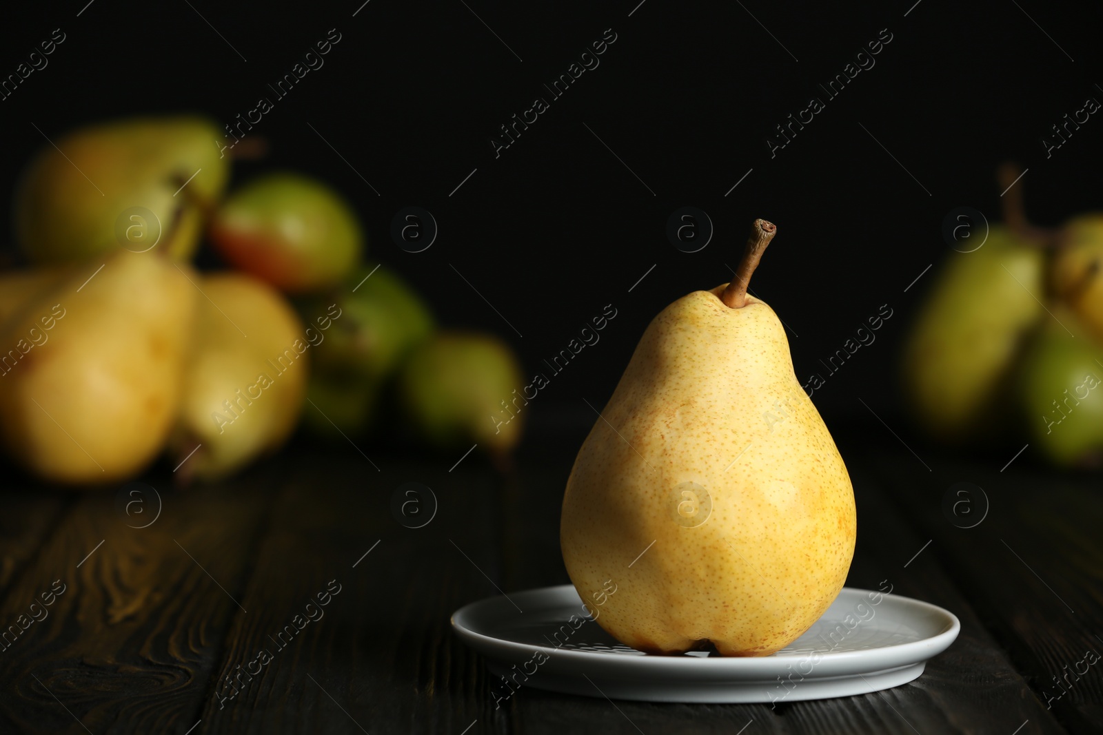 Photo of Plate with fresh ripe pear on table against blurred background