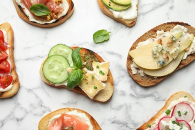 Photo of Different tasty bruschettas on marble background, flat lay