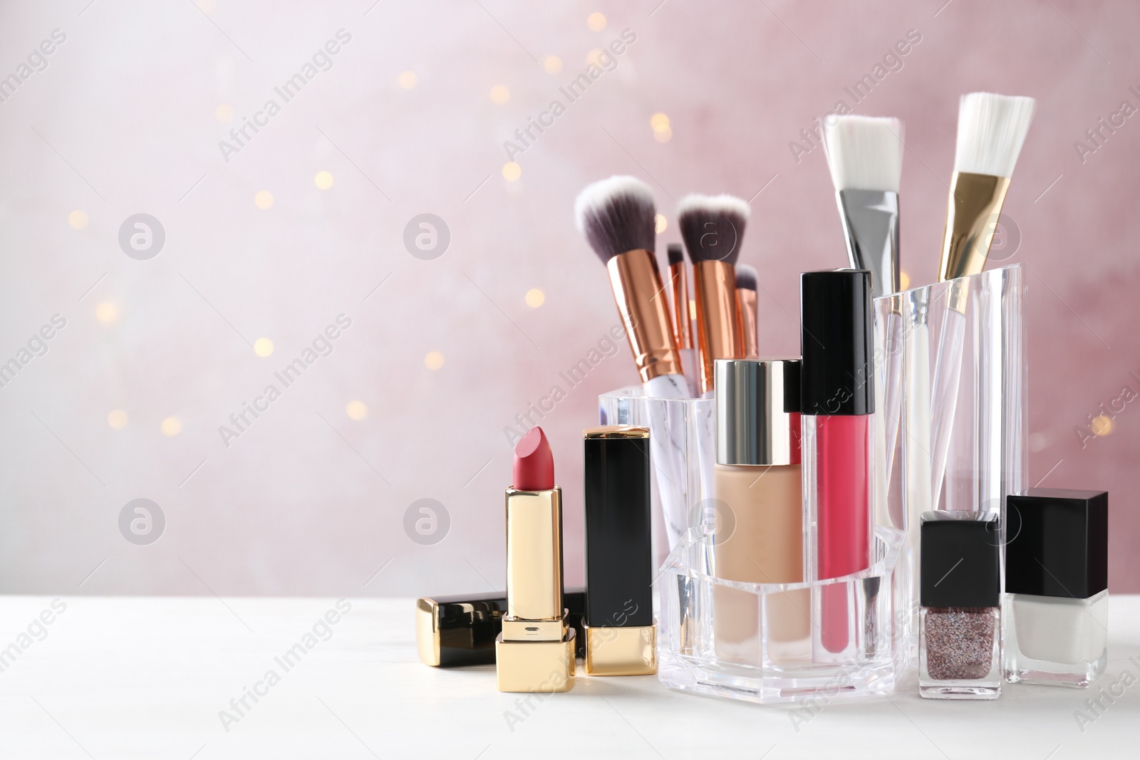 Photo of Makeup cosmetic products on white wooden table against pink background, space for text