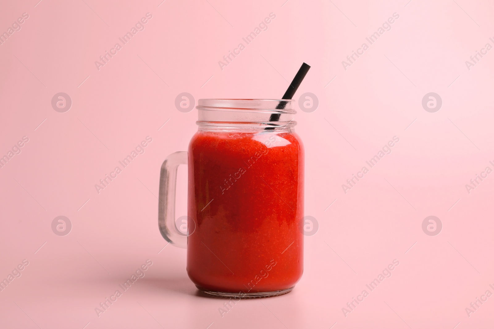 Photo of Mason jar with delicious berry smoothie on pink background