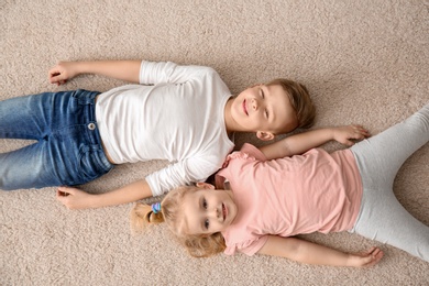 Photo of Cute little children lying on cozy carpet at home, top view