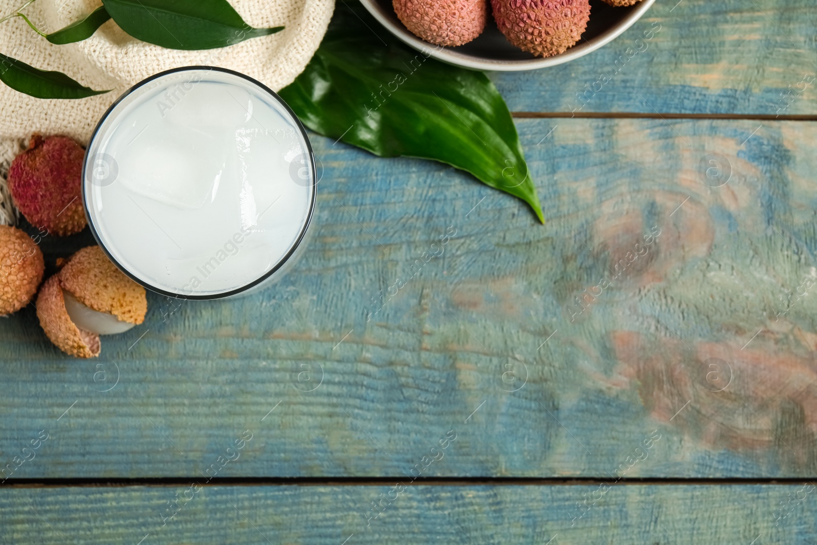 Photo of Fresh lychee juice and fruits on blue wooden table, flat lay. Space for text