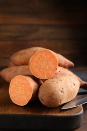 Photo of Whole and cut ripe sweet potatoes on wooden board