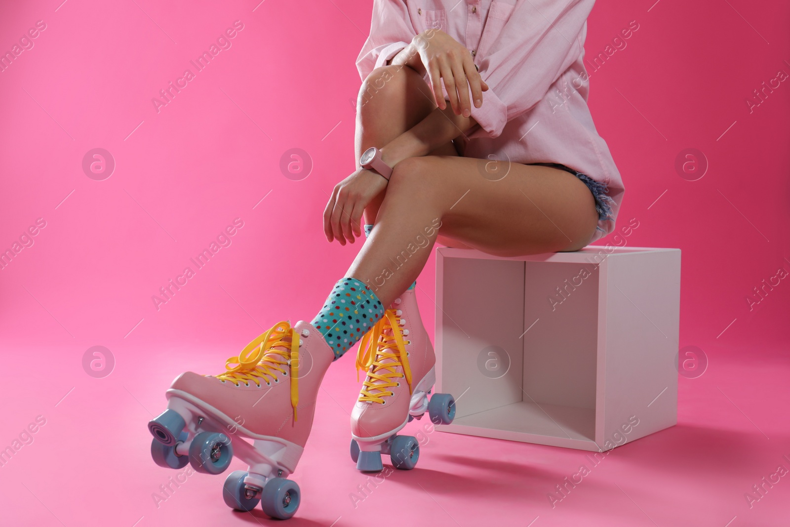 Photo of Young woman with retro roller skates on color background, closeup. Space for text