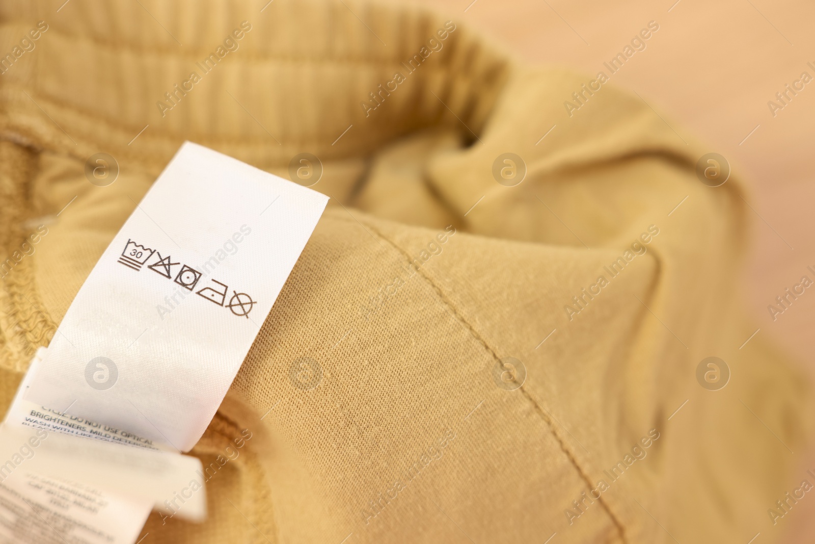 Photo of Clothing label on beige pants, closeup. Space for text