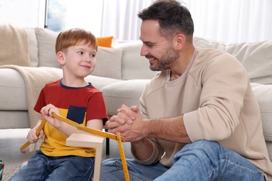 Photo of Father and son measuring shelf together at home. Repair work