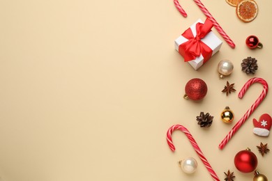 Photo of Flat lay composition with sweet candy canes and Christmas decor on beige background, space for text