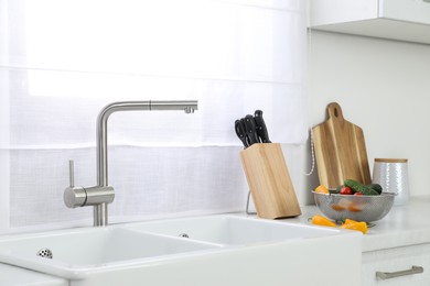 Photo of Modern sink and water tap on kitchen counter. Interior design
