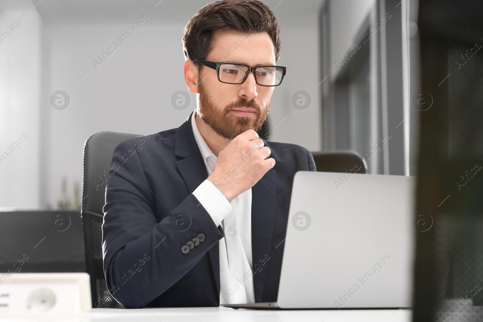 Photo of Man working on laptop at white desk in office