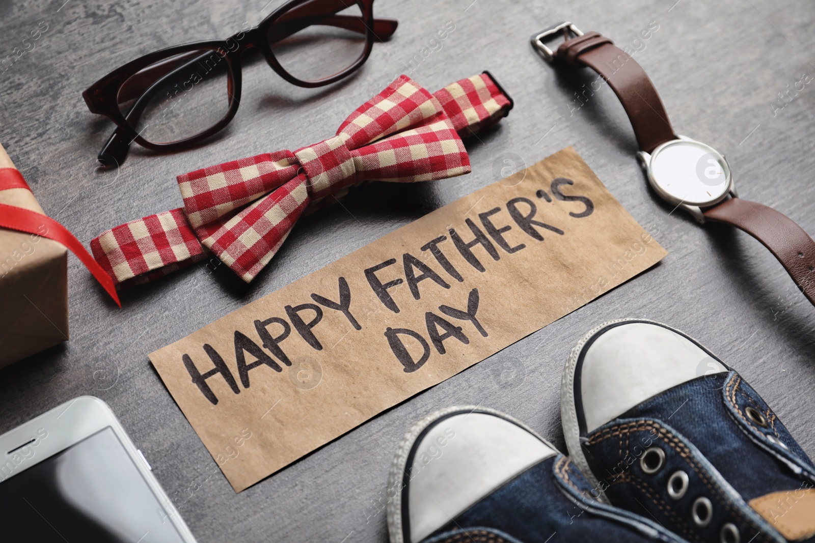 Photo of Small shoes, different gifts and card with words HAPPY FATHER'S DAY on wooden background