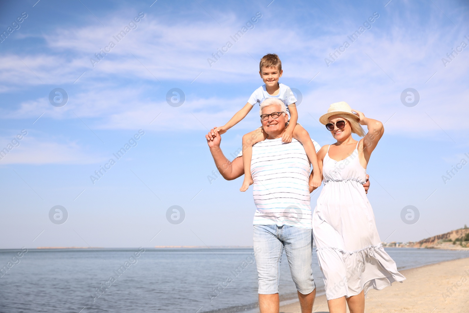 Photo of Cute little boy with grandparents spending time together on sea beach