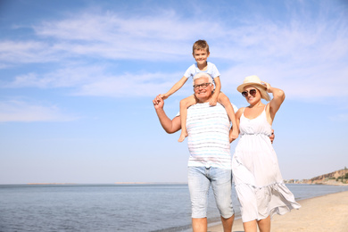 Cute little boy with grandparents spending time together on sea beach