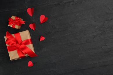 Photo of Gift boxes and paper hearts on black background, flat lay with space for text. Valentine's Day celebration