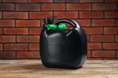 Black plastic canister on wooden table against brick wall