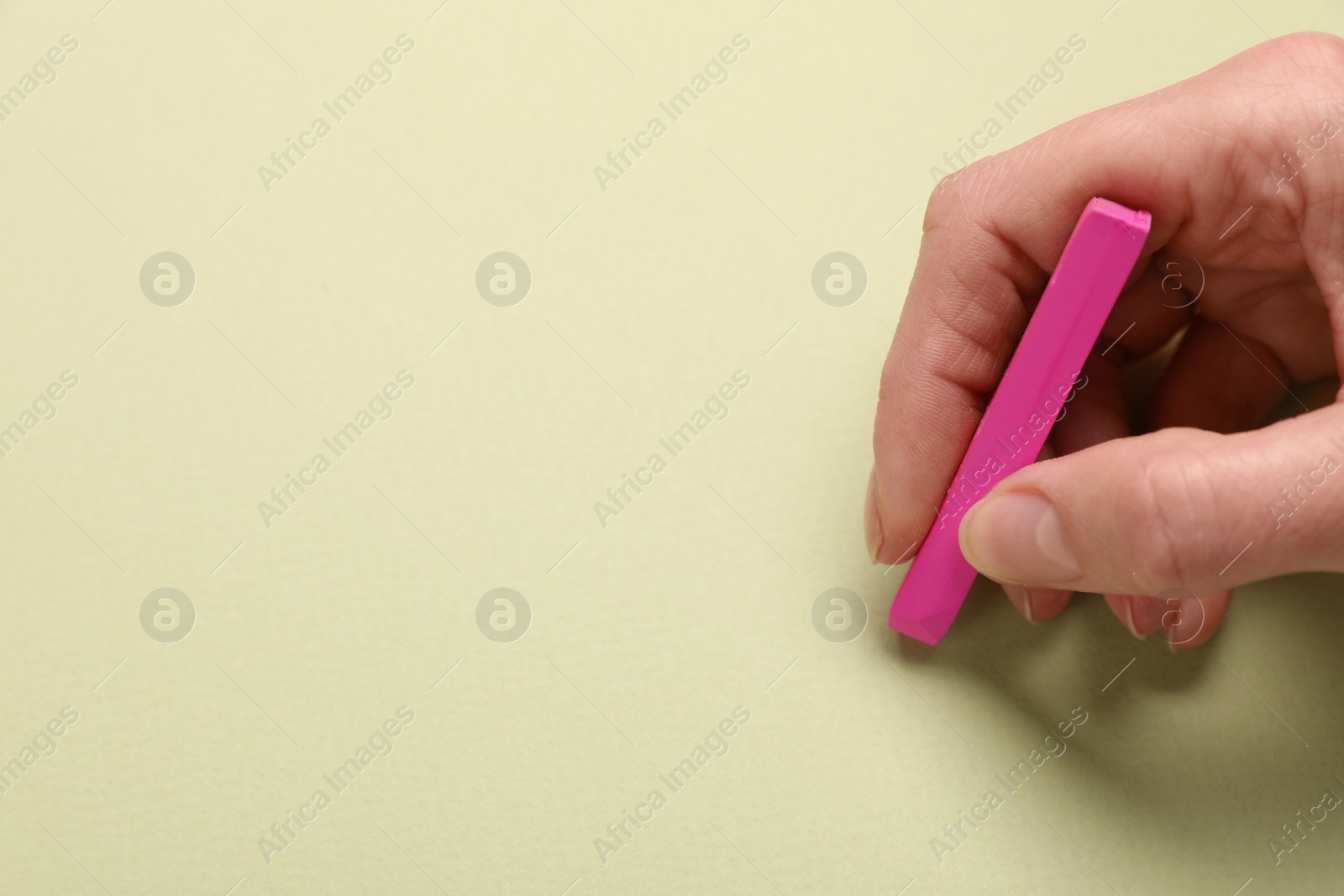 Photo of Woman drawing on light green paper with pastel, closeup. Space for text