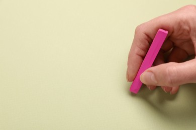 Photo of Woman drawing on light green paper with pastel, closeup. Space for text