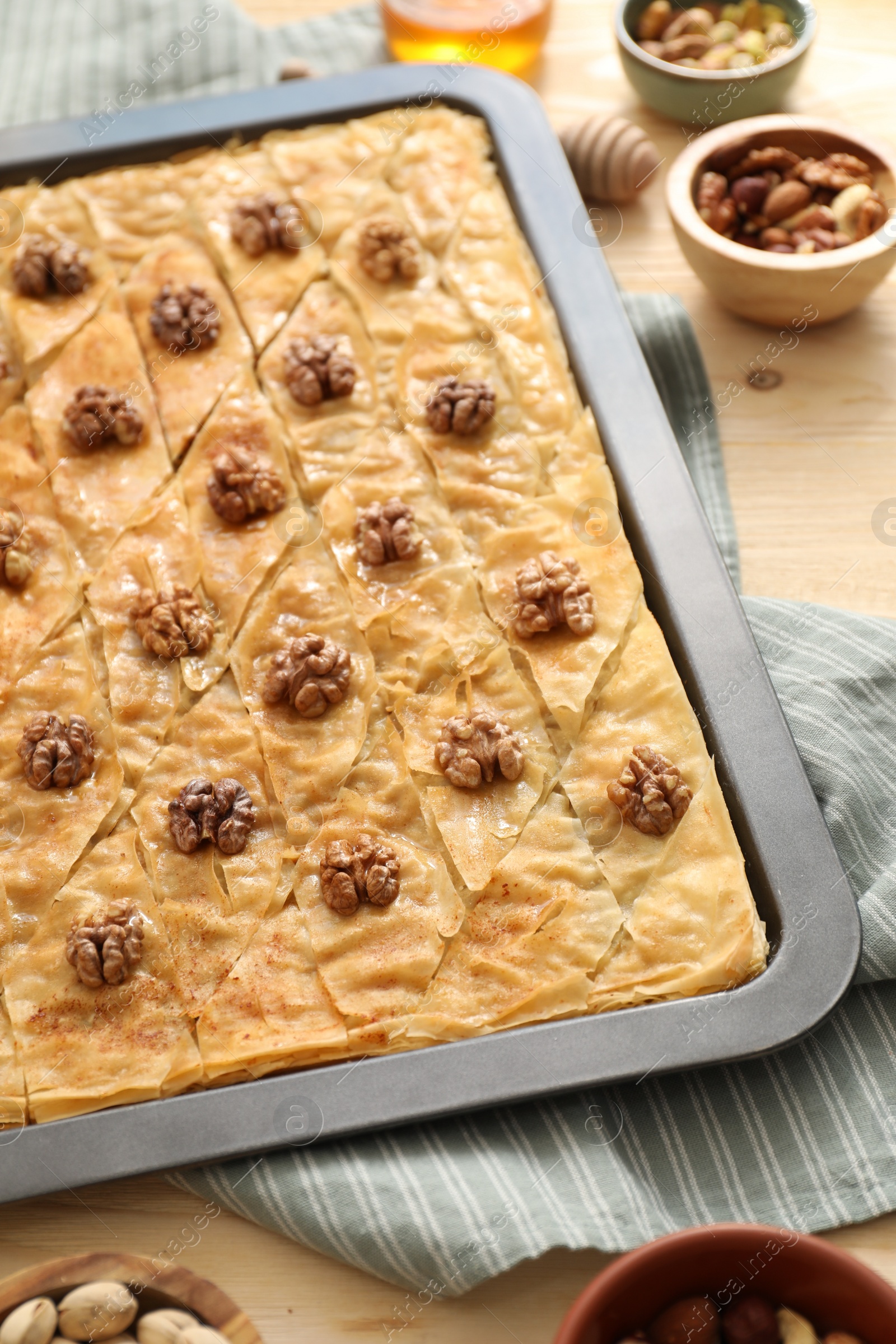 Photo of Delicious baklava with walnuts in baking pan on wooden table