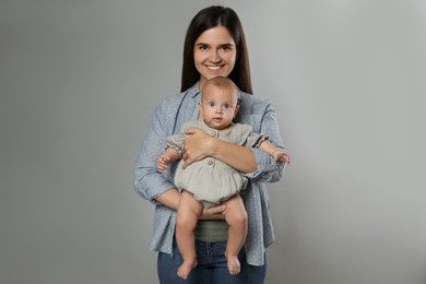 Photo of Beautiful mother with her cute baby on grey background