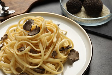 Photo of Tasty fettuccine with truffle on grey table, closeup