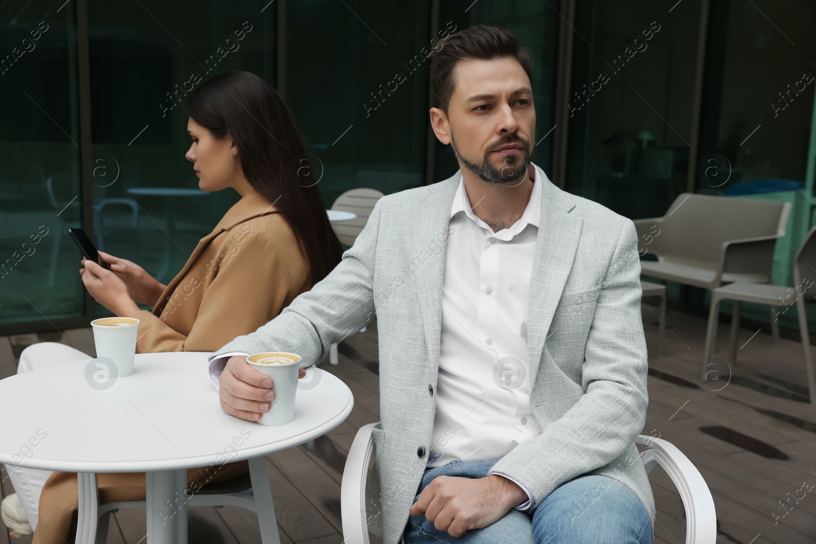 Photo of Upset arguing couple in outdoor cafe. Relationship problems