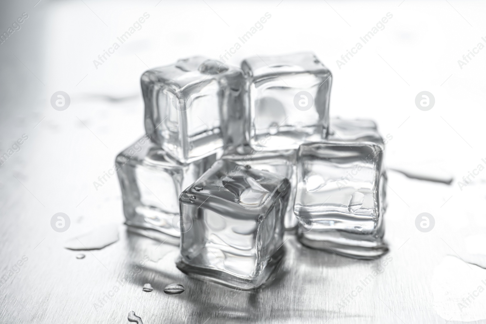 Photo of Crystal clear ice cubes with water drops on metal surface, closeup