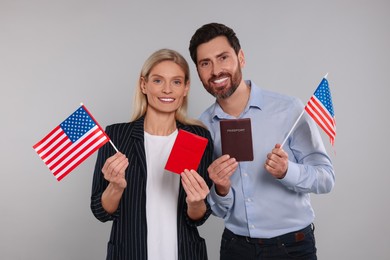 Immigration. Happy couple with passports and American flags on gray background