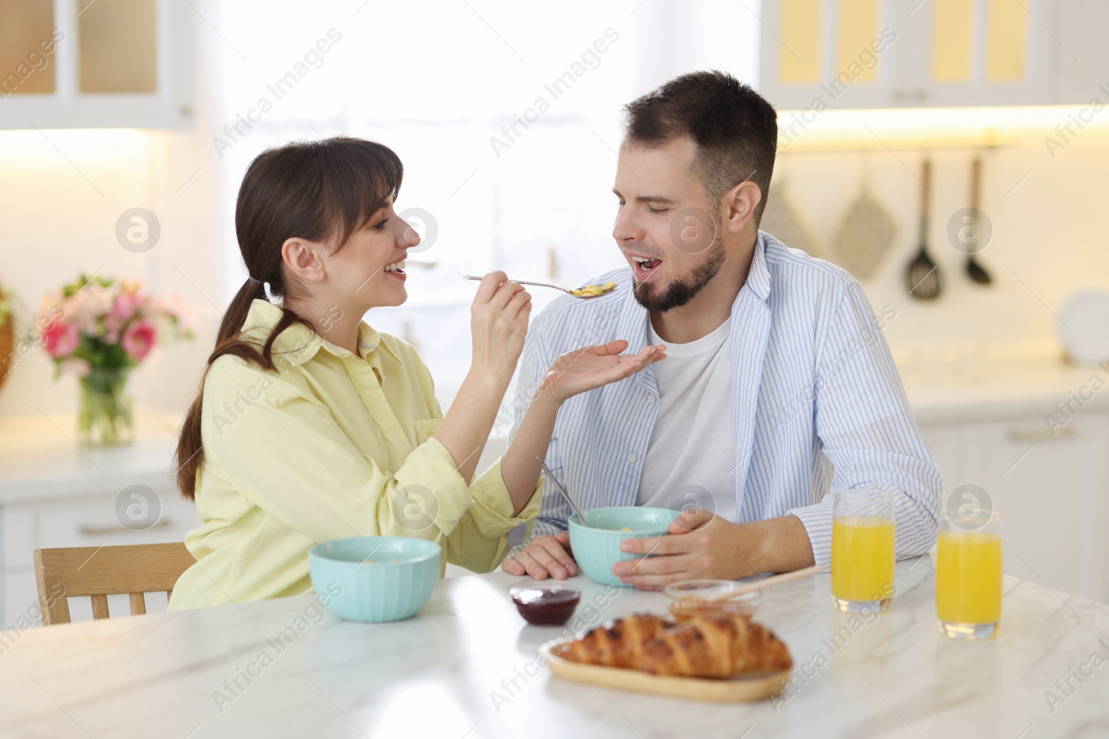 Photo of Tasty breakfast. Happy wife feeding her husband at home