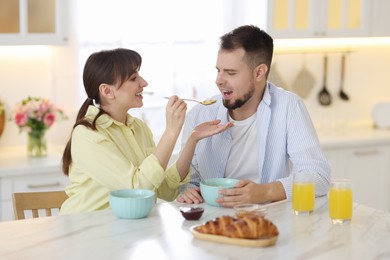 Photo of Tasty breakfast. Happy wife feeding her husband at home