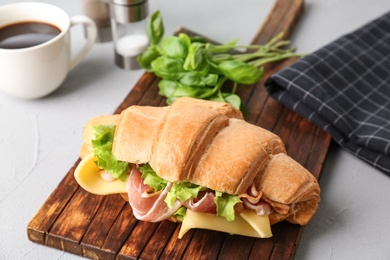 Tasty croissant sandwich with bacon on table