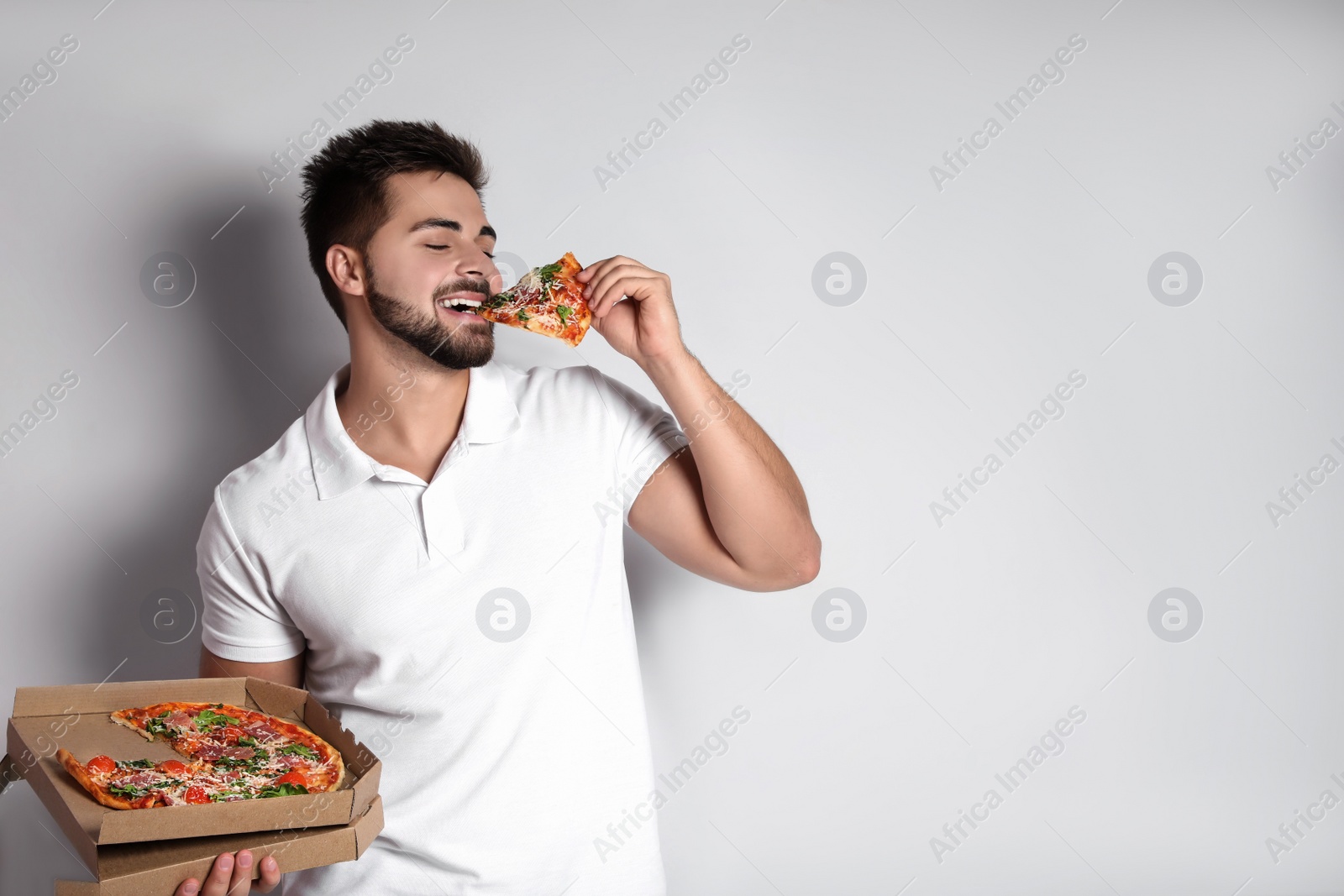 Photo of Handsome man eating pizza on white background, space for text