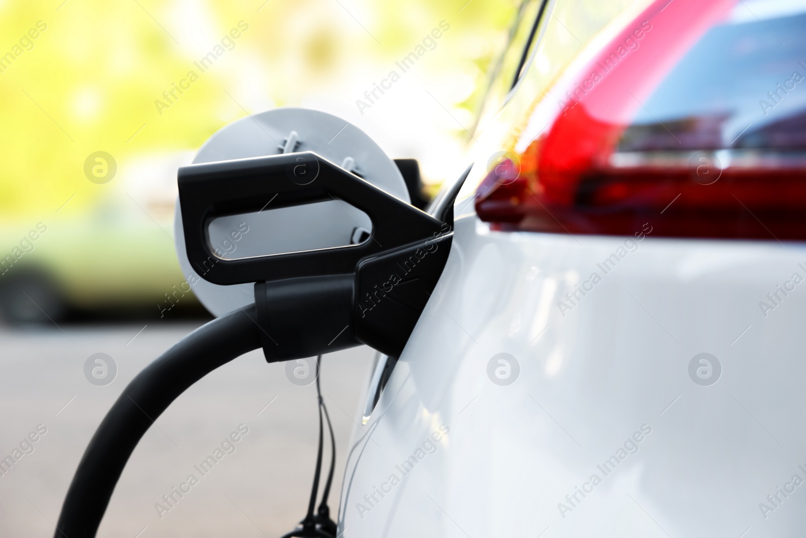 Photo of Charging modern electric car from station outdoors, closeup