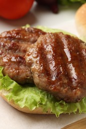 Photo of Delicious fried patties, lettuce and bun on board, closeup. Making hamburger