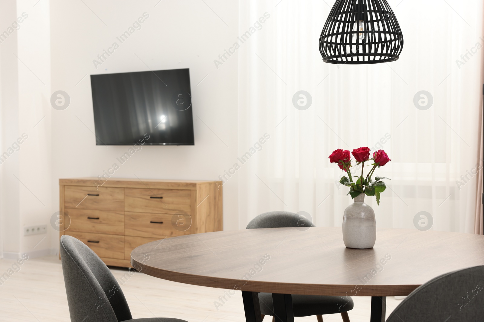 Photo of Chairs and table with vase of red rose flowers in dining room. Stylish interior