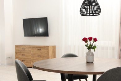 Chairs and table with vase of red rose flowers in dining room. Stylish interior