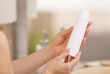 Photo of Young woman holding deodorant in bathroom, closeup