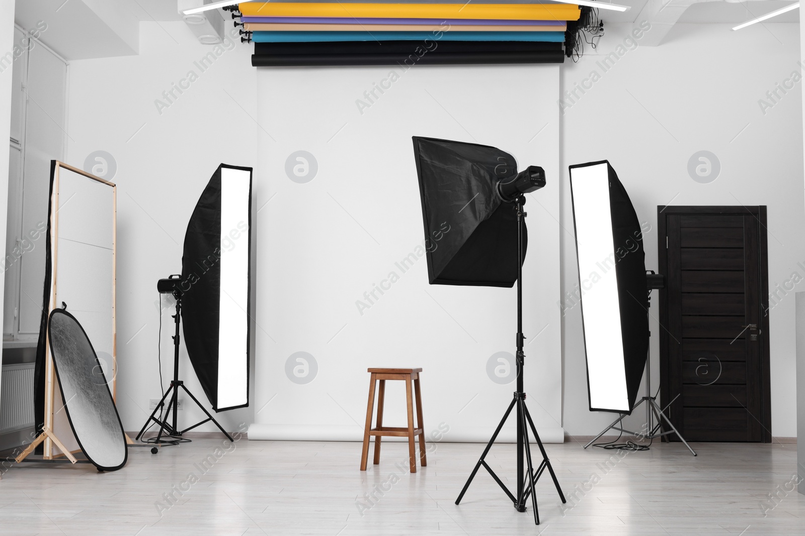 Photo of White photo background, stool and professional lighting equipment in studio