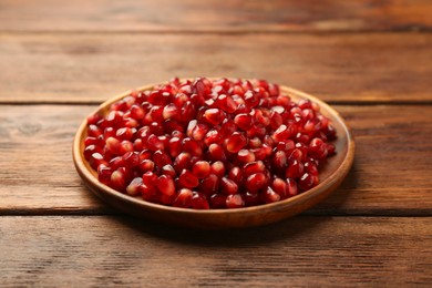 Photo of Tasty ripe pomegranate grains on wooden table