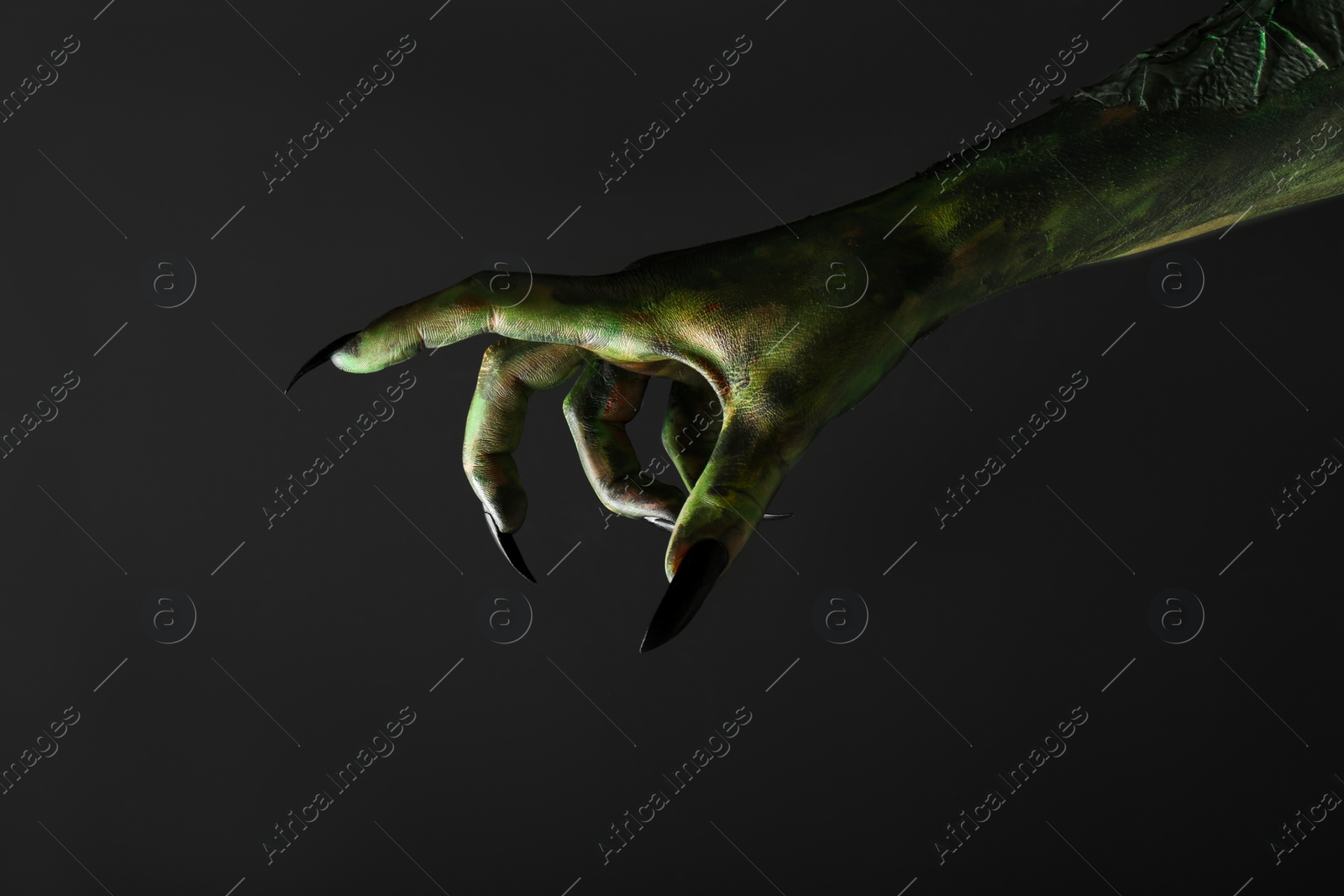 Photo of Scary monster on black background, closeup of hand. Halloween character